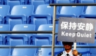 Ein Wachmann hält ein Schild mit der Aufschrift Bitte Ruhe! vor leeren Sitzen während eines Spiels beim Tennisturnier in Shanghai. Foto: dpa