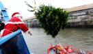 Ein Weihnachtsmann wirft im Hamburger Hafen einen Tannenbaum von dem Hafenrundfahrtsschiff Hamburg auf ein Feuerwehrschiff. Die Weihnachtsbäume wurden zum 13. Mal an große wie auch kleine Schiffe im Hafen als Weihnachtsgruß aus der Hansestadt verteilt.  Foto: dpa