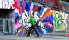 Ein junge Frau schiebt ihr Fahrrad unter dem Schriftzug point of no return einen mit Graffiti bemalten Fußgängerweg in Würzburg hoch.
 Foto: dpa