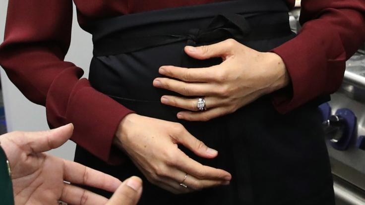 Schützend hält Meghan Markle die Hände vor ihren Babybauch.