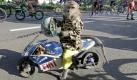 A trained monkey sits on a wooden replica of a racing motorbike made resembling that of Italian MotoGP rider Valentino Rossi's as cyclists ride past in Jakarta, Indonesia, Sunday, May 30, 2010. (AP Photo/Dita Alangkara) Foto: ap