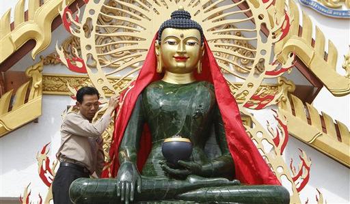 Ein Mitglied der buddhistischen Gemeinde in Homestead, Florida, hilft beim Enthüllen der weltgrößten Jade-Buddha-Figur. Die Figur aus kanadischem Jade wird aus Anlass des Thai-Neujahrsfestes gezeigt. Foto: ap