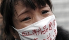 A woman, whose son was infected with HIV, wearing a face mask baring the words 'Blood products infect us with AIDS' cries during an AIDS awareness event on the World AIDS Day held at the Beijing's south railway station, Tuesday, Dec. 1, 2009. A group of protesters, who has infected HIV from blood transfer products including relatives of the victim disrupted a UNAIDS event, calling for greater support for people living with AIDS/HIV in China. (AP Photo/Andy Wong) Foto: ap