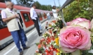 Fahrgäste betrachten am S-Bahnhof Solln in München die mit Blumen und Kerzen übersäte Stelle, an der der Fahrgast Dominik Brunner getötet wurde. Zum Gedenken an den brutal getöteten Münchner S-Bahnfahrgast Dominik Brunner veranstalten die beiden großen christlichen Kirchen heute Abend eine ökumenische Andacht. Foto: ddp