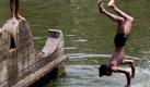 Im indischen Kalkutta erfrischt sich ein junger Mann mit einem Sprung in einen Teich. In Ostindien herrschen derzeit Temperaturen um die 40 Grad. Foto: Piyal Adhikary Foto: dpa