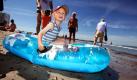 Timi spielt in seinem kleinen Schlauchboot am Strand von Warnemünde. Temperaturen bis zu 30 Grad und Sonnenschein locken Urlauber und Tagesgäste an die Ostseeküste von Mecklenburg-Vorpommern. Foto: dpa
