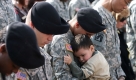 An unidentified solider, third from left, holds his son as the prayer Invocation is given by Col. Michael Lembke, III Corps Chaplain during the memorial ceremony for victims of the Fort Hood shooting held at U.S. Army's III Corps headquarters, Tuesday, Nov. 10, 2009, at Fort Hood, Texas. (AP Photo/Rodolfo Gonzalez, POOL) Foto: ap