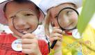 Maximilian und Johanna erkunden mit einer Lupe beim Tag der kleinen Forscher die Gegend am Bundespressestrand in Berlin. Tausende Kinder werden ihrem Beispiel am Donnerstag folgen: Überall im Bundesgebiet beteiligen sich dann Kitas an Deutschlands größter Bildungsinitiative Haus der kleinen Forscher und gehen naturwissenschaftlichen Phänomenen und technischen Fragen auf den Grund. Foto: dpa