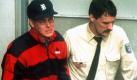 Das Archivbild vom 3.3.1995 zeigt den britischen Börsenhändler Nick Leeson (l) in Begleitung eines Polizeibeamten in Frankfurt am Main. Der 31 Jahre alte Finanzjongleur, der 1995 in Singapur wegen Betrugs in Milliardenhöhe zu sechseinhalb Jahren Haft verurteilt worden ist, leidet angeblich an Krebs. Seine Anwälte bemühen sich derzeit, eine vorzeitige Entlassung aus der Haft zu erreichen, bestätigte die britische Botschaft in Singapur am Donnerstag (6.8.1998). Leeson, der die traditionsreiche britische Bank Barings in den Zusammenbruch trieb, werde seit einigen Tagen wegen Darmkrebs in einem Gefängiskrankenhaus behandelt. dpa Foto: dpa