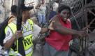 Ein Polizist in Haitis Hauptstadt Port-au-Prince greift nach einer Frau, die Lebensmittel aus einem durch das Erdbeben zerstörten Geschäft an sich nehmen wollte. Foto: ap