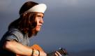 Ein junger Mann spielt gedankenversunken auf seiner Gitarre am Strand in Kalifonien. Foto: ap