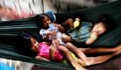 Kambodschanische Kinder liegen in einer Hängematte am Straßenrand von Phnom Penh und werden von ihrer Mutter in den Mittagsschlaf gewiegt. Foto: ap
