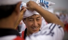 Ein chinesischer Trommelspieler bekommt Hilfe beim Anlegen des Kopfschmuckes. Die Trommler und Tänzer proben ihren Auftritt für den 60. Geburtstag Chinas. Foto: ap