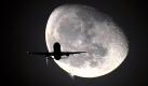 Ticket to the Moon: Die Silhouette eines Flugzeugs vor dem Mond über London. Foto: Andy Rain Foto: dpa