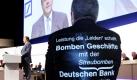 Während Deutsche Bank Chef Josef Ackermann auf der Bilanzpressekonferenz des Unternehmens spricht, protestiert ein Teilhaber mit dem Aufdruck Leistung die Leiden schafft - Bomben Geschäfte der Deutschen Streubomben Bank auf seinem Shirt. Foto: dapd