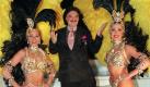 Der Münchner Modeschöpfer Rudolph Moshammer zeigt sich nach der Europa-Galapremiere des Pariser Lidos im Deutschen Theater in München mit zwei Tänzerinnen (Archivfoto vom 06.03.1998, nach einem Autounfall ist sein Unterschenkel geschient). Moshammer wurde am Freitagmorgen (14.01.2005) tot in seiner Wohnung entdeckt. Er fiel nach Angaben der Staatsanwaltschaft einem Gewaltverbrechen zum Opfer. Genauere Einzelheiten seien bisher nicht bekannt, sagte ein Sprecher der Staatsanwaltschaft München I am Freitag. Foto: Volker Dornberger dpa +++(c) dpa - Bildfunk+++ Foto: dpa
