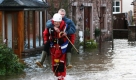Ein Retter trägt einen Mann aus seinem überfluteten Haus in Cumbria, Großbritannien. Schwere Regenfälle haben den Fluss Eamont über die Ufer treten lassen. Wegen der Überflutungen mussten hunderte Menschen evakuiert werden. Foto: dpa
