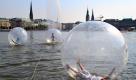 Besucher gehen in Hamburg in luftgefüllten Kunststoffbällen, sogenannten Walk Water Balls, auf der Binnenalster. Das Museum für Kunst und Gewerbe und die Stiftung Viva con Agua luden im Rahmen der Ausstellung Klimakapseln zum Spaziergang ein. Foto: ddp