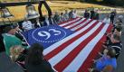 Besucher des Flug-93-Mahnmals in Pennsylvania,USA, nehmen am Freitagabend an einer Gedenkveranstaltung teil. Sie halten eine Flagge, auf der die Flugnummer aufgedruckt ist. Die Passagiere hatten das gekaperte Flugzeug am 11. September 2001 in ihre Gewalt und dann zum Absturz auf einem Feld gebracht. Foto: ap