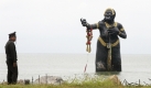 Die thailändische Polizei steht vor einer Statue, die als Teil einer Protestaktion gegen die Regierung ins Meer gesetzt wurde. In Thailand findet zurzeit das Asean-Gipfeltreffen statt, Asean ist ein Verband südostasiatischer Länder. Foto: dpa