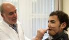 Johannes C. Bruck, Chefarzt der Klinik für Ästhetische Chirurgie am Berliner MLK, zeigt die Gesichtsrekonstruktion an Mohamed Z. Foto: Sebastian Kahnert Foto: dpa