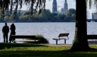 Ein Paar geht in Hamburg an der Außenalster in der Sonne spazieren. Foto: dpa