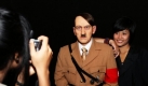 Eine Besucherin lässt sich neben der Wachsfigur Adolf Hitlers in Pattaya, Thailand, fotografieren. Das neueröffnete Wachfigurenmuseum hat mit Plakaten, auf denen Hitler zu sehen war und Hitler ist nicht tot geschrieben stand, geworben und international Aufsehen erregt. Foto: dpa