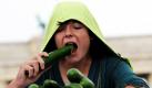 Lewin Grabo schützt sich während der Teilnahme an einem Gurkenwettessen vor dem Brandenburger Tor in Berlin vor dem Regen. Der Vegetarierbund feiert mit der Veranstaltung den Freispruch von Gurken, Tomaten und Salat vom Verdacht, Auslöser der Darmkrankheit durch den EHEC-Erreger zu sein. Foto: dpa