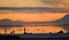Besucher beobachten den Sonnenuntergang vom gefrorenen Watt nahe des Elderberry Park in Anchorage/Alaska. Das Abendlicht setzt den Vulkan Mt. Spurr ins rechte Licht. Foto: ap