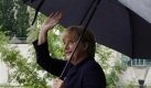 Bundeskanzlerin Angela Merkel geht am Sonntag, 24. August 2008, beim Tag der offenen Tür der Bundesregierung mit einem Regenschirm durch den Garten des Bundeskanzleramtes in Berlin. Foto: ap