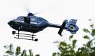 Ein Polizist fotografiert am Sonntag in Berlin am Fundort einer Leiche von einem Helikopter aus. Ein unbekannter Toter ist am Sonntagmittag in Berlin-Französisch-Buchholz gefunden worden. Foto: dapd