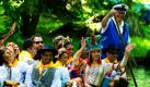 Teilnehmer der Folklorelawine aus Brasilien sitzen in einem Spreewaldkahn und fahren über ein Fließ im brandenburgischen Lübbenau. Die zehnte Internationale Folklorelawine hat am gleichen Tag in der Lausitz mit einem Festumzug und einem Kahnkorso begonnen. An dem Jubiläumsfestival der Kulturen nehmen in diesem Jahr Folkloregruppen aus 16 Ländern teil, wie eine Sprecherin der Kreisverwaltung Spree-Neiße mitteilte. Foto: dpa