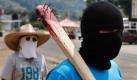 An einer Absperrung im mexikanischen Cheran stehen vermummte Anwohner Spalier. Die Männer des Ortes haben begonnen, die lokale Sicherheit in die eigenen Hände zu nehmen, indem sie die Zugänge der Stadt mit errichteten Barrikaden aus Sandsäcken und gestohlenen Waffen bewachen. Foto: dapd