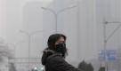 A masked woman looks away while crossing a street in the city center shrouded in fog, caused by air pollution, in Beijing Monday, Dec. 7, 2009. Negotiators in Copenhagen are trying to set targets for controlling emissions of carbon dioxide and other global warming cases, including by the leading contributors, China and the United States. (AP Photo/Andy Wong) Foto: ap