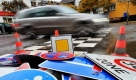 Ein Auto fährt im Frankfurter Stadtteil Nieder-Erlenbach an einem Haufen alter Verkehrsschilder vorbei. Statt einer Vielzahl von Verkehrsschildern soll der Verkehr durch gegenseitige Rücksichtsnahme und gleichberechtigtes Miteinander geregelt werden.  Foto: dpa