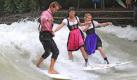 Simon (l-r), Tanja und Kathi surfen am Freitag (03.09.2010) in München auf der Welle im Eisbach. Anlässlich des DVD- und Blu-ray Starts von dem Kinofilms 'Keep Surfing', der von Surfern handelt, die auf der beliebten Welle im Eisbach in München surfen, waren einige Eisbach-Surfer kurz vor dem Start des 200. Oktoberfest in Dirndl und Lederhose unterwegs. Foto: Marc Müller dpa/lby +++(c) dpa - Bildfunk+++ Foto: dpa