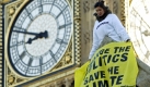 Ein Klima-Aktivist schwingt ein Transparent auf dem Dach der Houses of Parliament in London. Foto: ap