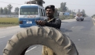 Ein pakistanischer Polizist verschanzt sich hinter einem LKW-Reifen, um einen Kontrollpunkt in Shakhupura nahe Lahore zu sichern. Foto: ap
