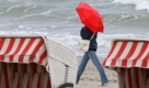 Am Ostseestrand von Graal-Müritz bei Rostock ist eine Spaziergängerin im Regen unterwegs. Bei regelmäßigen Schauern, 16 Grad Luft- und 18 Grad Wassertemperatur hilft nur wetterfeste Bekleidung. Foto: dpa