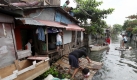 In Manila hüpft eine Frau nach einem Sturm mit Überflutungen von einem improvisierten Floß zum nächsten. Taifun Santi wird auf den Philippinen am Samstag mit voller Kraft erwartet. Foto: ap