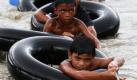 Philippinische Kinder in Marikina, östlich von Manila, nutzen Schläuche als Schwimmhilfen und hangeln sich an einem Seil über das Wasser des Flusses Marikina, um für den Fall einer Flut zu wissen, wie sie sich retten können. Ein Jahr ist es her, dass Marikina und und Manila von schweren Fluten betroffen waren, die der Typhoon Ketsana ausgelöst hatte. Foto: dpa
