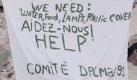 Mit einem Banner bitten Haitianer um Wasser, Lebensmittel, Lampen und Planen. Foto: dpa