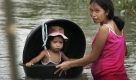 A mother floats her daughter through floodwaters in Taytay township, Rizal province east of Manila, Philippines, Saturday, Oct. 3, 2009. Powerful winds toppled power poles and trees Saturday in the northern Philippines as the second typhoon in eight days bore down on the country. (AP Photo/Wally Santana) Foto: ap