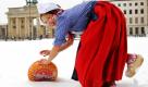 Mit Mühe rollt Hollands Käse-Lady Frau Antje vor dem Brandenburger Tor in Berlin ihren Käse durch den tiefen Schnee zur Grünen Woche. Die 75. Internationale Grüne Woche in den Hallen unter dem Funkturm mit 1600 Ausstellern aus 56 Ländern öffnet für die Besucher vom 15. bis 24. Januar ihre Tore. Foto: dpa