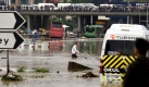 Ein Kleinbus ist in den Wassermassen steckengeblieben. Schaulustige beobachten das Szenario von der Brücke aus.  Foto: dpa