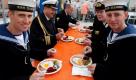 Zwei Matrosen der Royal Navy sitzen am Samstag (23.07.11) beim Weltrekordversuch im Labskaus-Essen in Wilhelmshaven mit deutschen und britischen Marineoffizieren am Tisch und essen Labskaus. 10.613 Portionen des norddeutschen Traditionsessens müssen am Samstag gegessen werden, um den Rekord aus dem Jahr 2005 zu brechen. Foto: Focke Strangmann/dapd