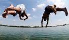 Zwei junge Männer springen in den Guggenberger See in der Oberpfalz. Auch in den nächsten Tagen soll das Wetter in Bayern mit Temperaturen über 30 Gad hochsommerlich warm bleiben. Erst zum Wochenende sagen die Meteorologen fallende Temperaturen voraus.  Foto: dpa