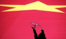 Eine chinesische Frau lässt einen Spielzeugvogel vor einer riesigen chinesischen Flagge, im Rahmen des 60. Geburstags Chinas, aufsteigen. Foto: ap