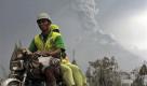 Dorfbewohner verlassen auf ihren Mopeds die Gefahrenzone. Der Berg Merapi in Indonesien spuckt Lava und Rauch. Die Bewohner fürchten um ihr Leben. Foto: ap