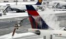 Ein Flugzeug der Fluggesellschaft Delta Airlines wird am Samstag (09.01.10) auf dem Flughafen in Frankfurt am Main enteist, waehrend im Hintergrund Raeumfahrzeuge die Start- und Landbahnen von Schnee befreien. Tief 'Daisy' hat den Verkehr am Frankfurter Flughafen stark beeintraechtigt. Am Samstagmorgen seien bereits mehr als 200 Fluege ausgefallen, sagte ein Sprecher auf ddp-Anfrage. Betroffen waren 102 Starts und 104 Landungen. Vor allem innerdeutsche Fluege und Kontinentalfluege mussten gestrichen werden.
 Foto: ddp